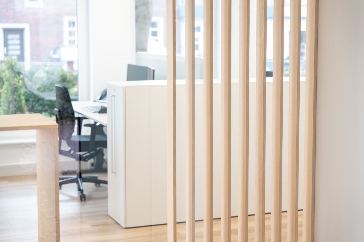 Eine maßgefertigte Lamellenstruktur aus hellem Holz zoniert die Räume